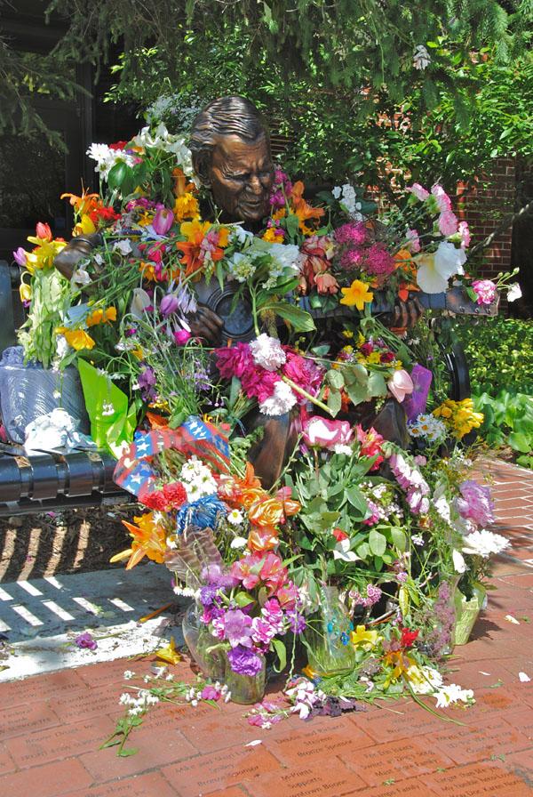 The local statue of Doc Watson is covered in flowers left in memory for the famous musician. Photo by Olivia Wilkes  |  The Appalachian
