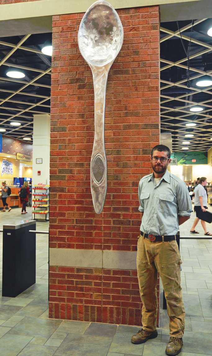 Adjunct Instructor of Art Joe Bigley stands by the aluminum spoon recently unveiled in the Central Dining Hall promenade. Bigley used up to 100 pounds of recycled aluminum material to create the sculpture. Maggie Cozens | The Appalachian