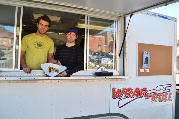 Evan Kawala and Alan Russel, employees of Boone’s new food truck Wrap-N-Roll, display a pork belly wrap to passerbys on Howard Street.