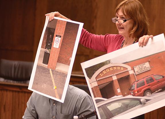 Member of the Watauga County Board of Elections Kathleen Campbell holds up photographs of the outside of Legends during Wednesday night's Board of Elections meeting. Campbell argued against the relocation of voting spaces to the nightclub instead of the student union. Photo by Maggie Cozens | The Appalachian