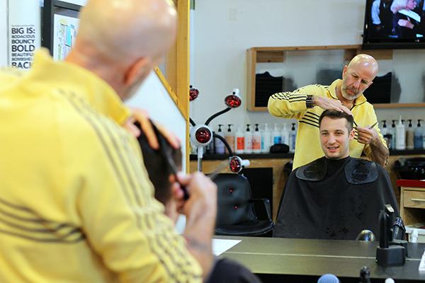 Mayoral candidate John Mena, who is currently the owner of the hair salon Haircut 101, cuts the hair of sophomore exercise science major Adam Pinkerton. Photo by Molly Cogburn  |  The Appalachian