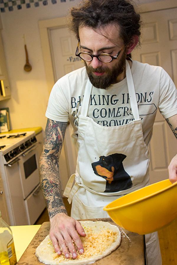 Appalachian alumnus Michael Story prepares a Jamaican-inspired pizza in his kitchen Monday evening to document on his vegetarian food blog. Story started his blog to document the meals he creates, which can be found at dudeshesvegetarian.com, in hopes that it “provides a way for young fellows to impress their veggie ladies.” Photo by Paul Heckert  |  The Appalachian
