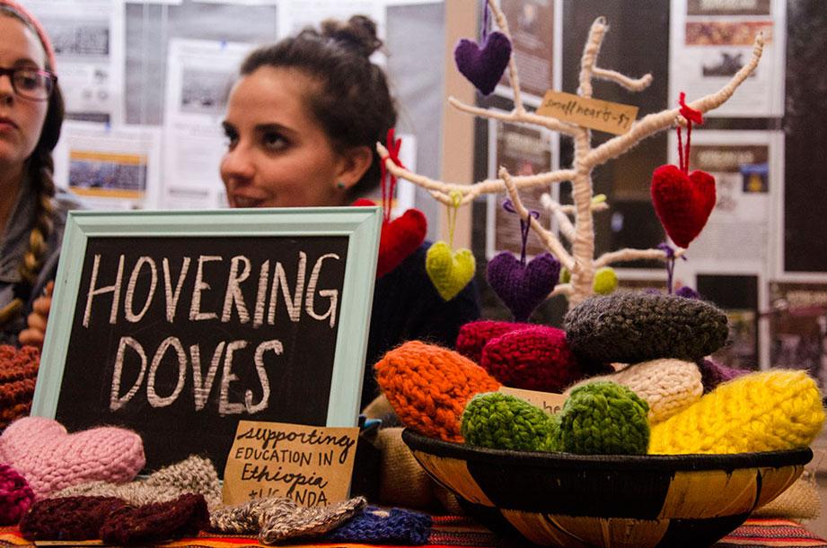 Junior social work majors Emma Reynolds (left) and Maddy Burns (right) discuss their scarf knitting business Hovering Doves at a booth during the Old Time Fiddlers Convention. The two have sold hundreds of scarves, knitting up to five a day to raise money for their own and others service trips abroad. The scarves can be seen and purchased at hoveringdoves.com. Photo by Kim Reynolds | The Appalachian